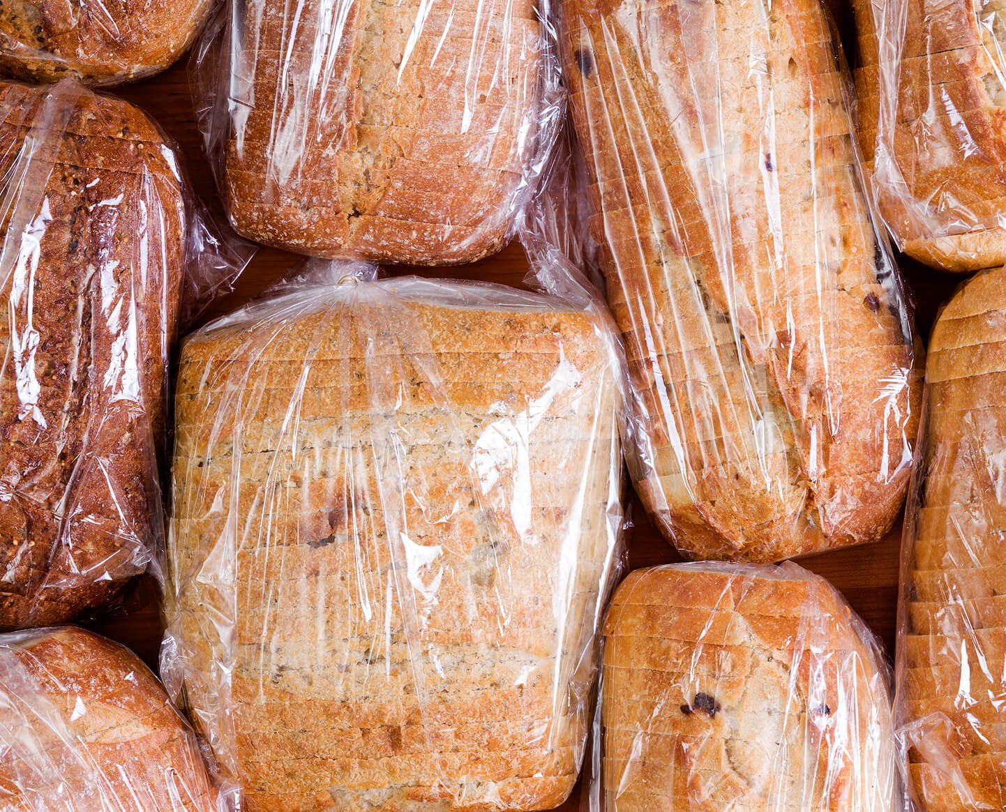 An assortment of sliced loaves of bread in bags.